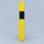 A tall rectangular yellow bollard with a wide black horizontal band across the middle and a silver metal base, shown on a plain light gray studio background.